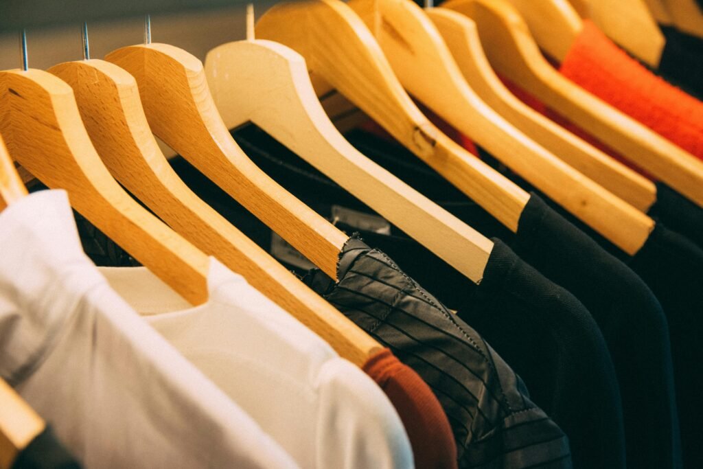 pexels-photo-996329-996329 A close-up view of a row of clothes on wooden hangers, showcasing various fabrics and colors in a wardrobe setting.